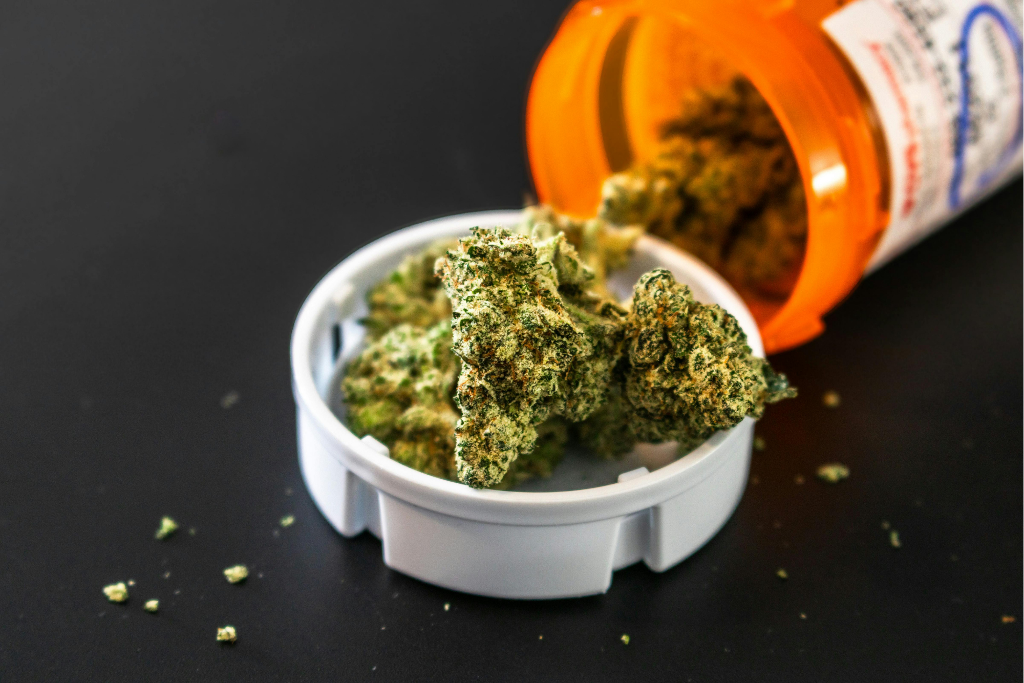 an open orange medicine vial with hemp inside and sitting on the cap