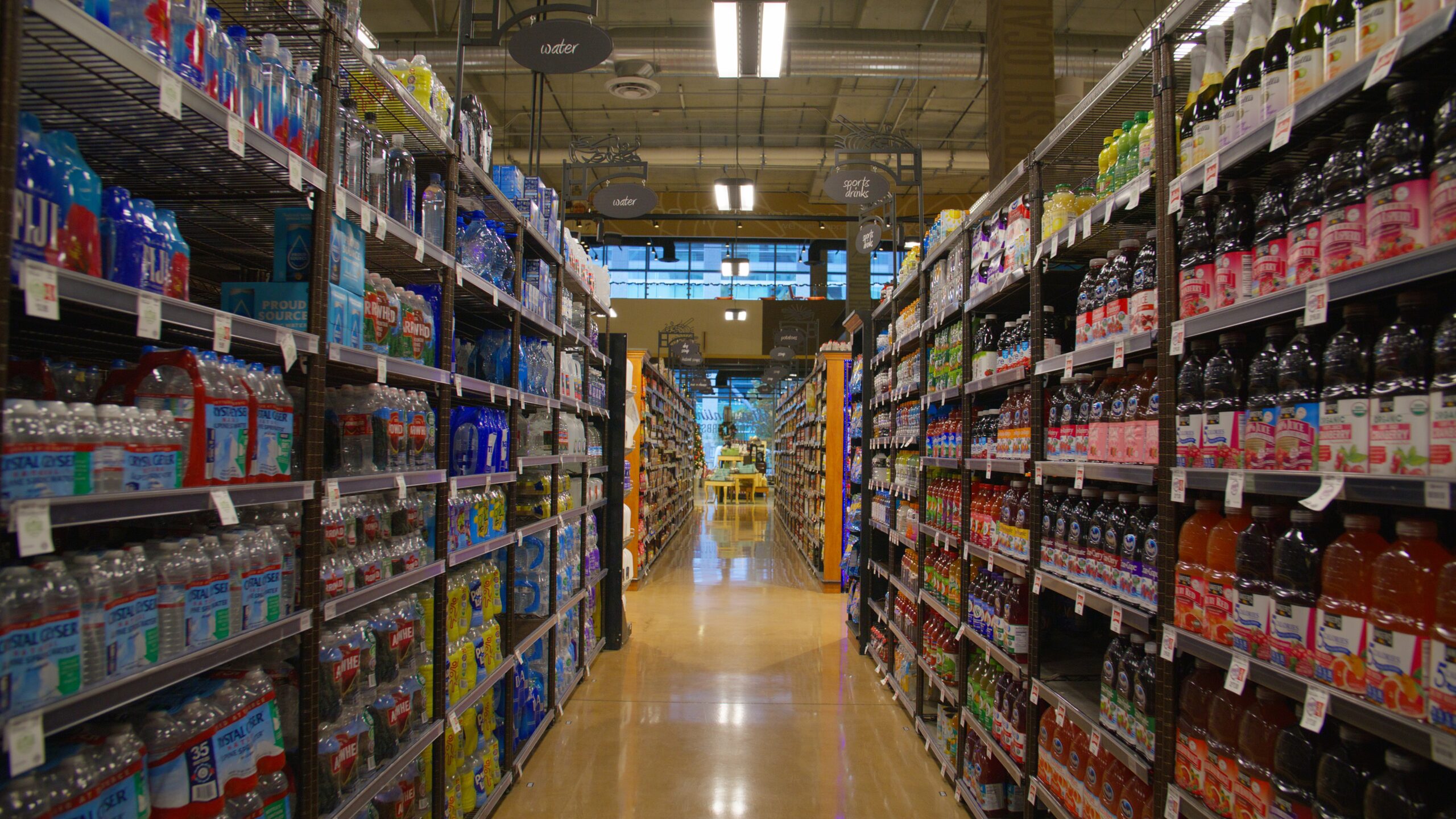 looking down the juice and water bottle aisle of a vague grocery store