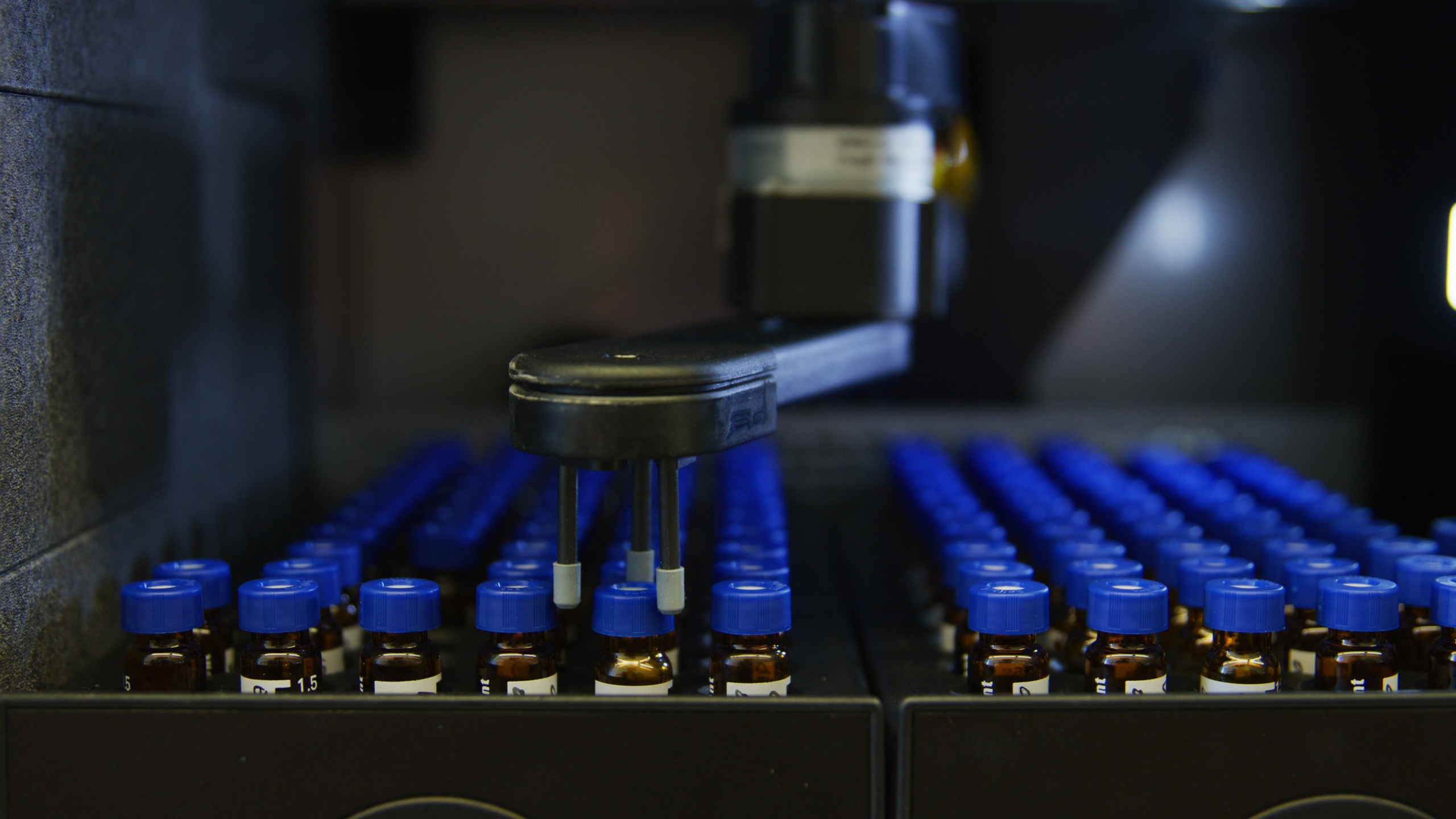 Lab samples with blue lids being moved around with a machine