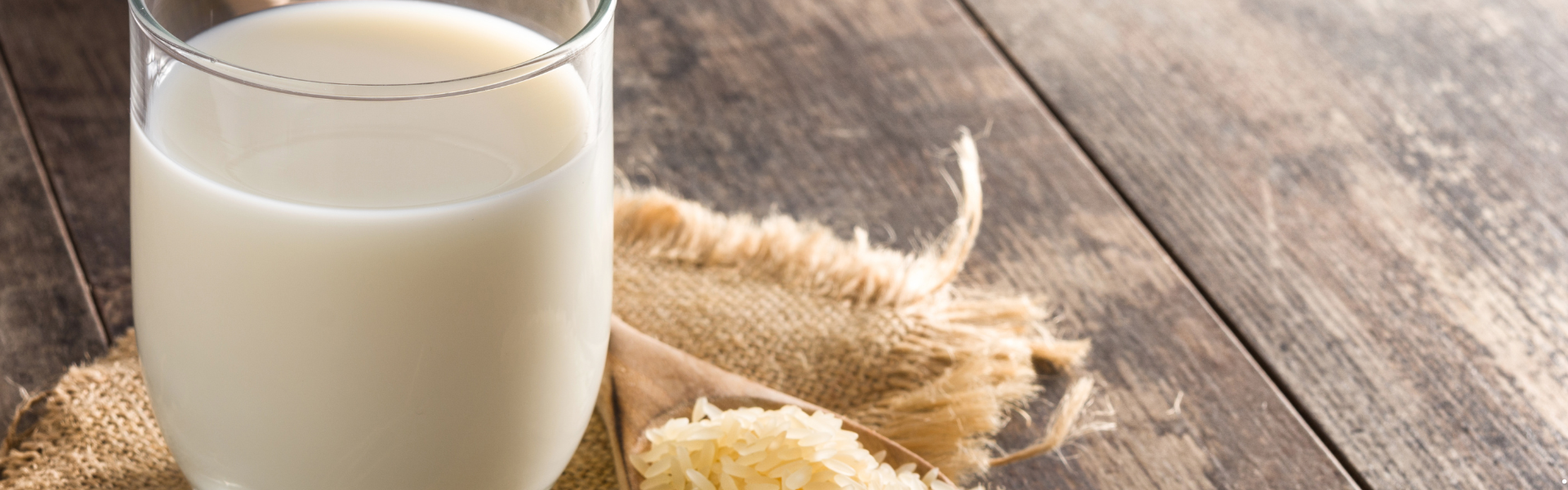 a glass of milk sitting on a piece of brown burlap fabric on a wooden table