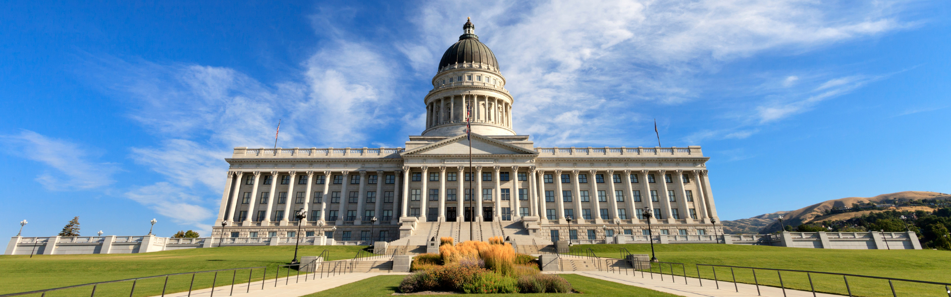 A picture of the front of the Utah State Capitol during summertime with green grass and blue sky
